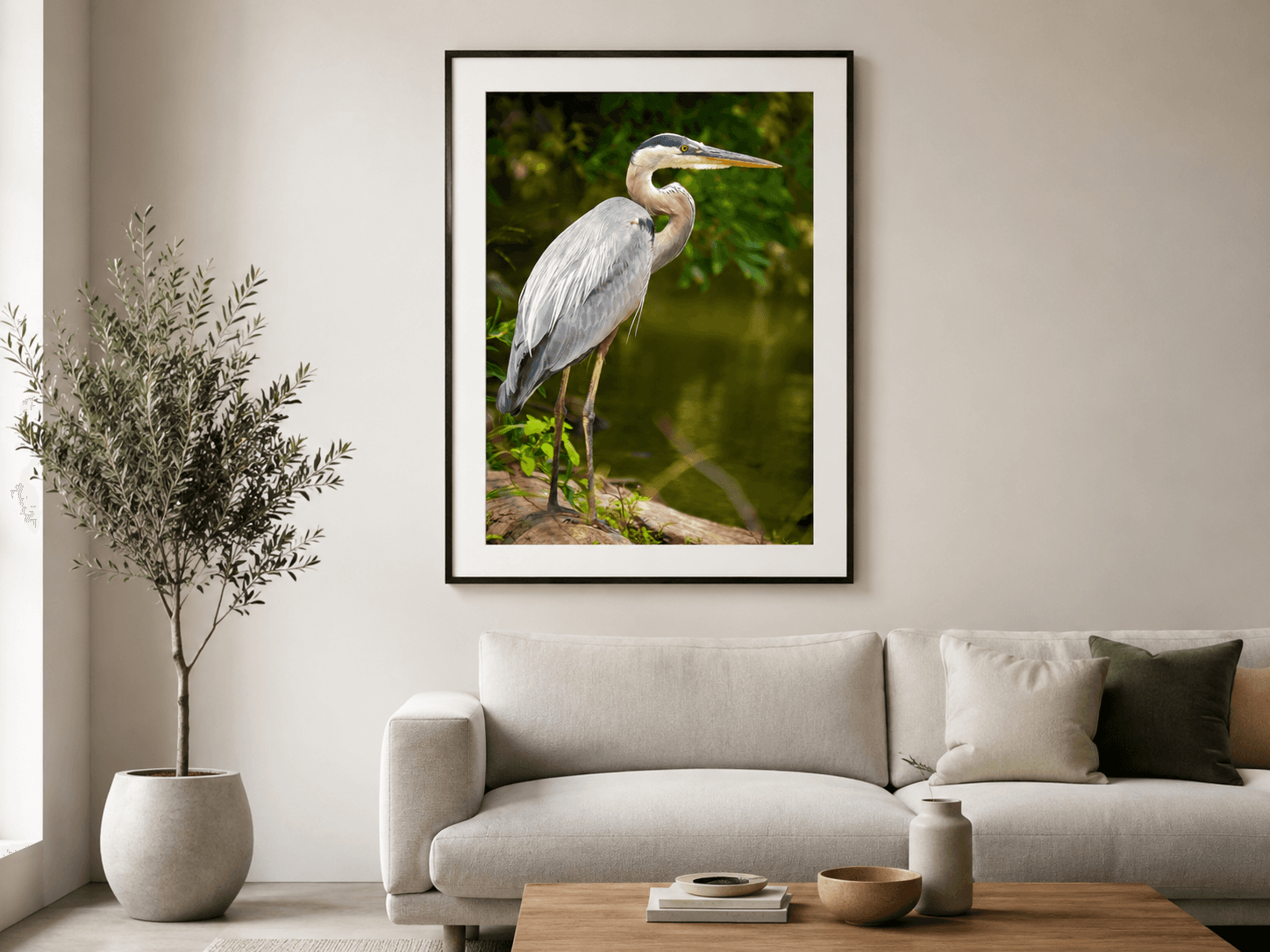 Great Blue Heron portrait print in a slim black frame above a linen sofa in a bright minimal living room