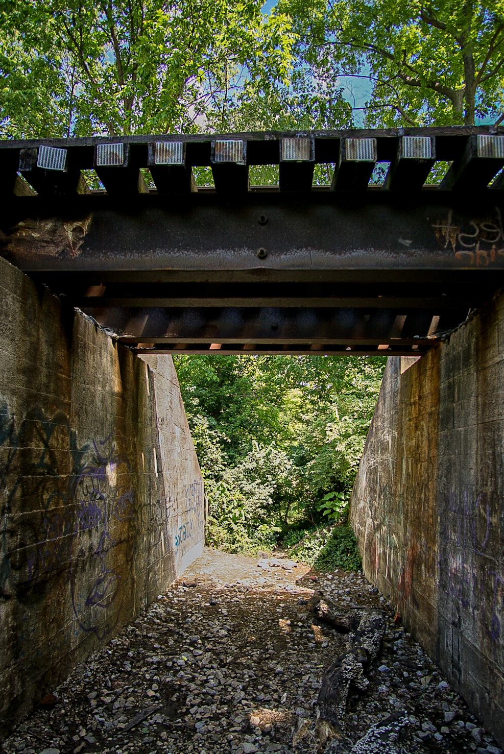 Layered spray paint beneath a concrete overpass.
