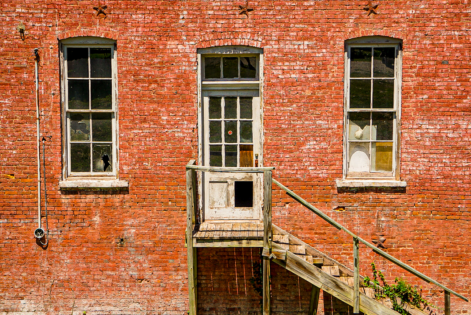 A decaying exterior staircase beside blown-out windows.