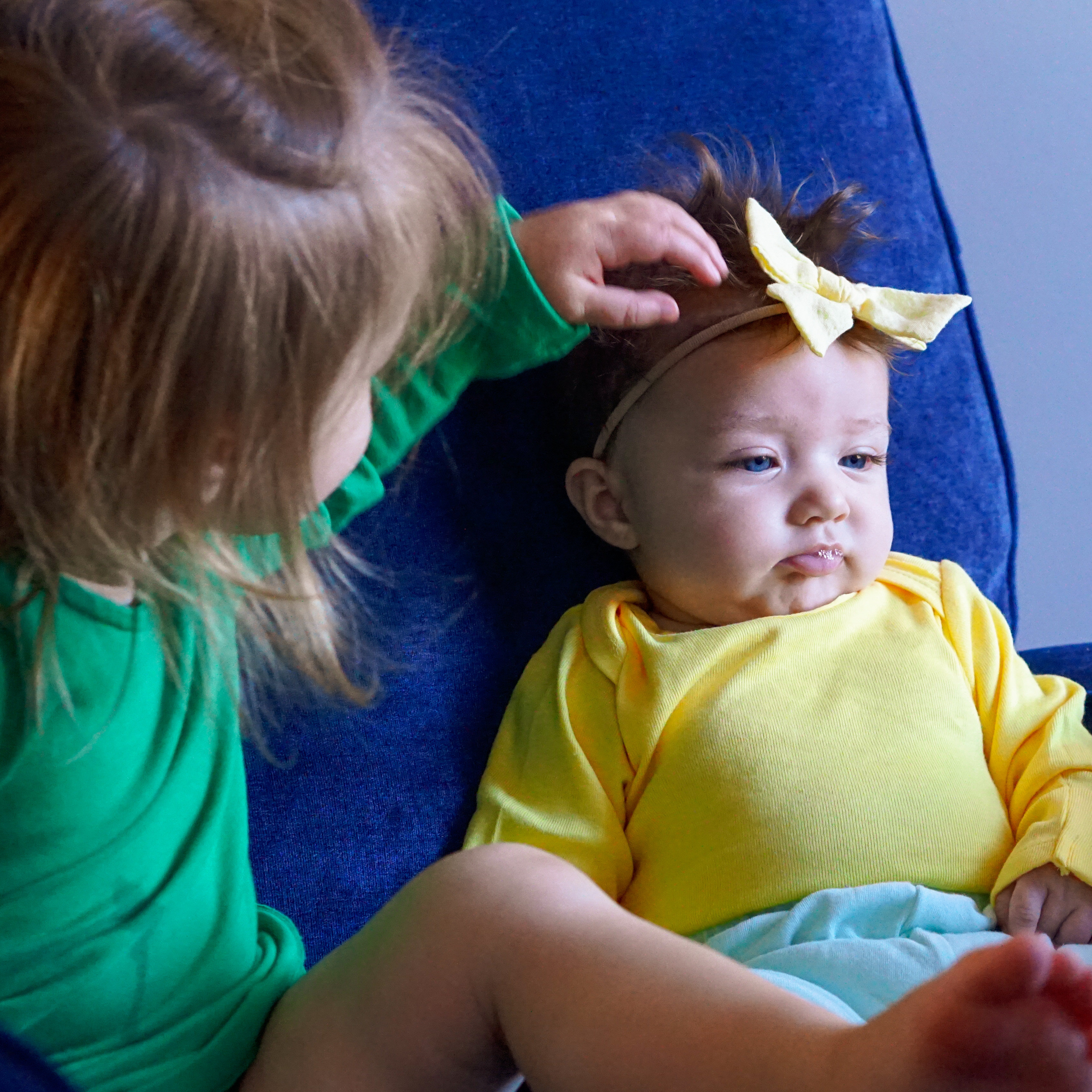 Young child gently touching newborn sibling's head